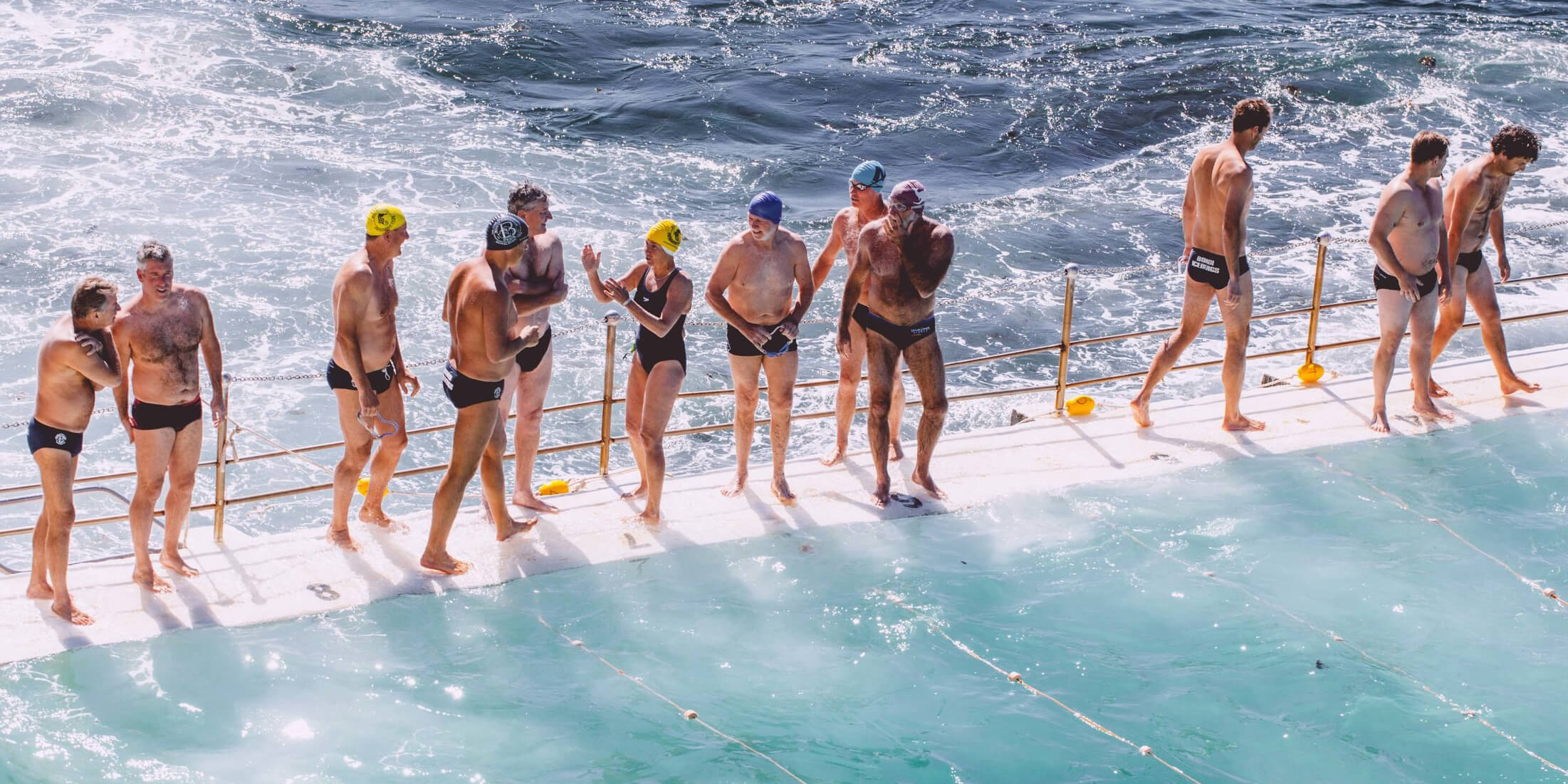 Large group of swimmers standing by an ocean pool 