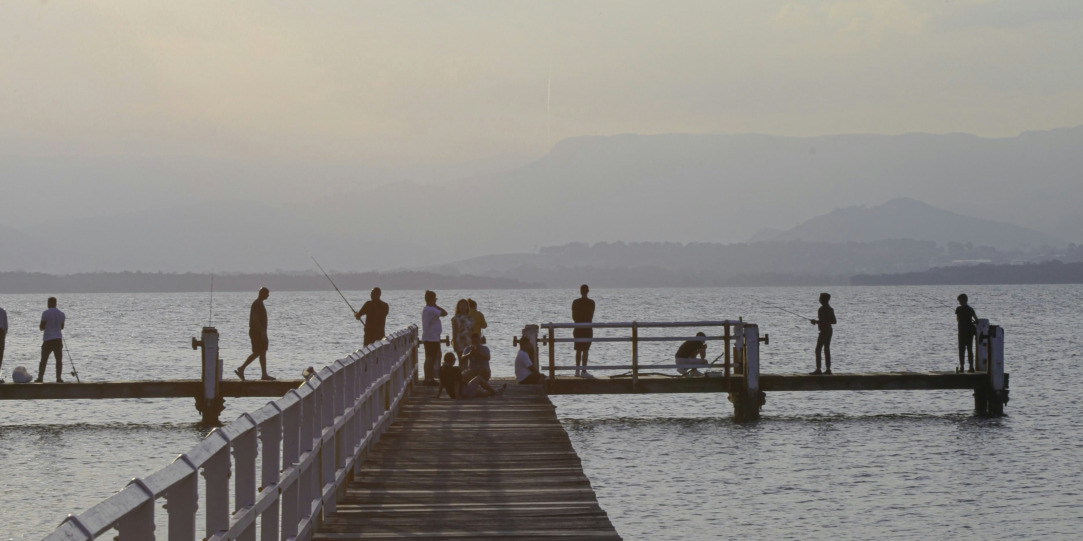 Fishing pier with people fishing in silhouette