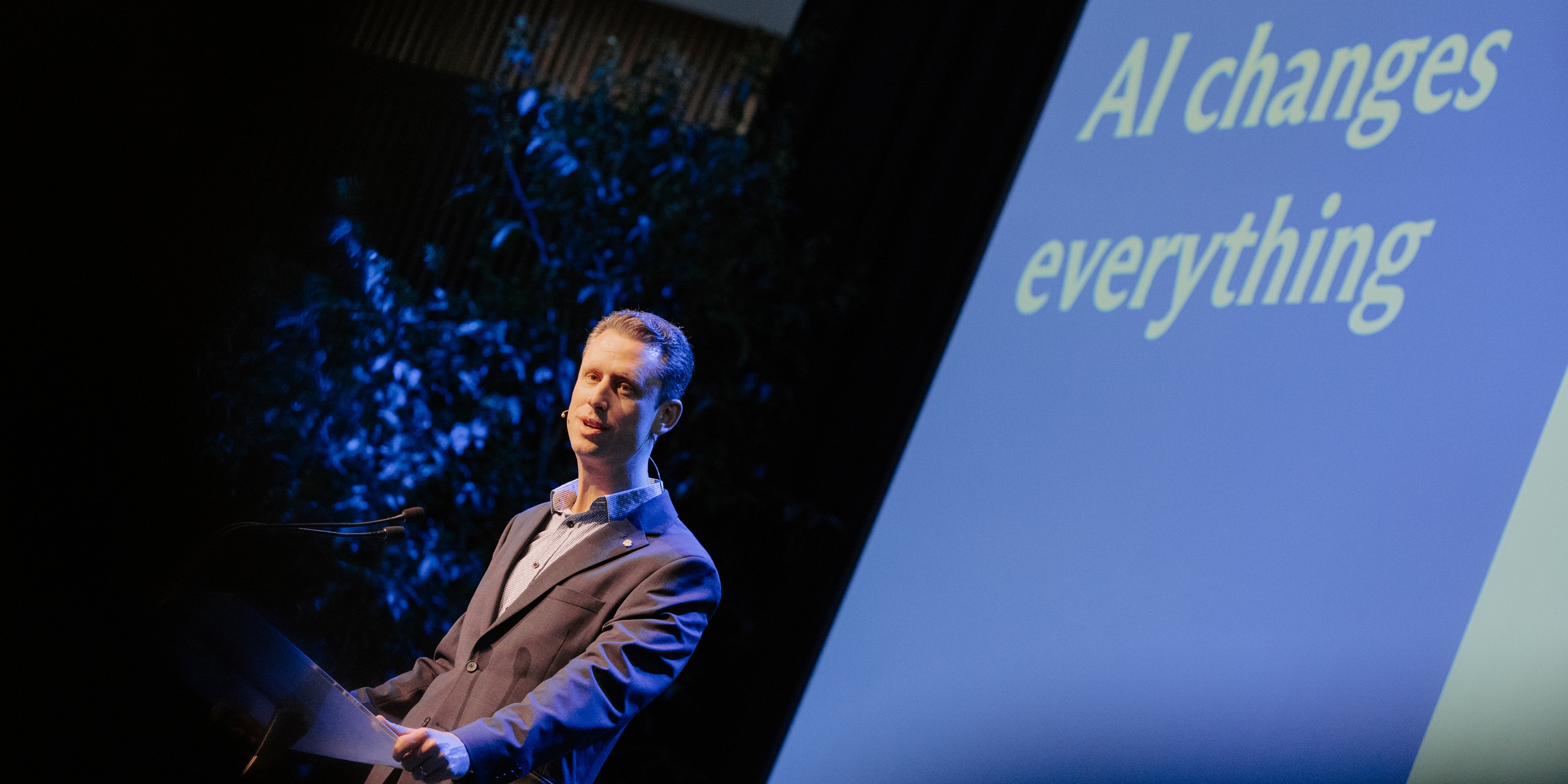 Presenter with "AI changes everything" on slide behind them